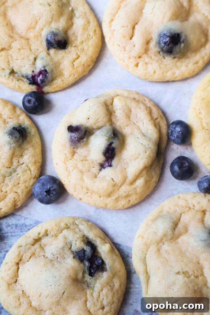 parchment paper with lemon blueberry cookies with half a lemon and blueberries