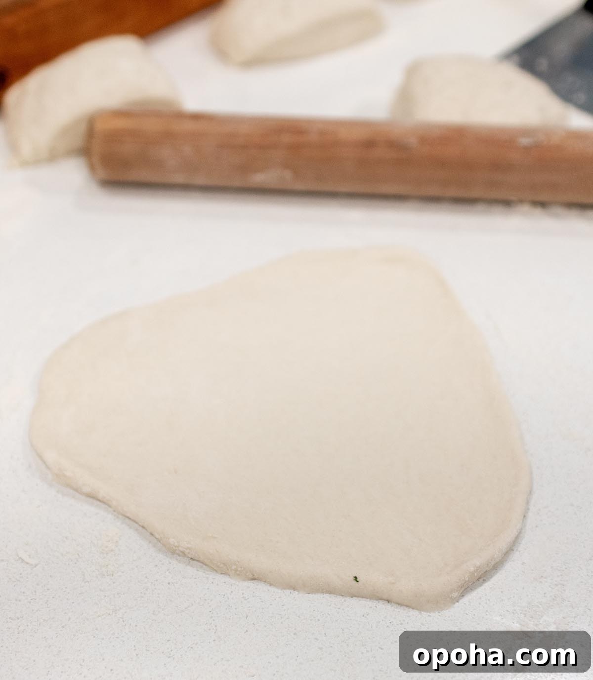 Sourdough Discard Naan Recipe: Crispy, Chewy Flatbread 6 A piece of sourdough naan being rolled out onto the counter.