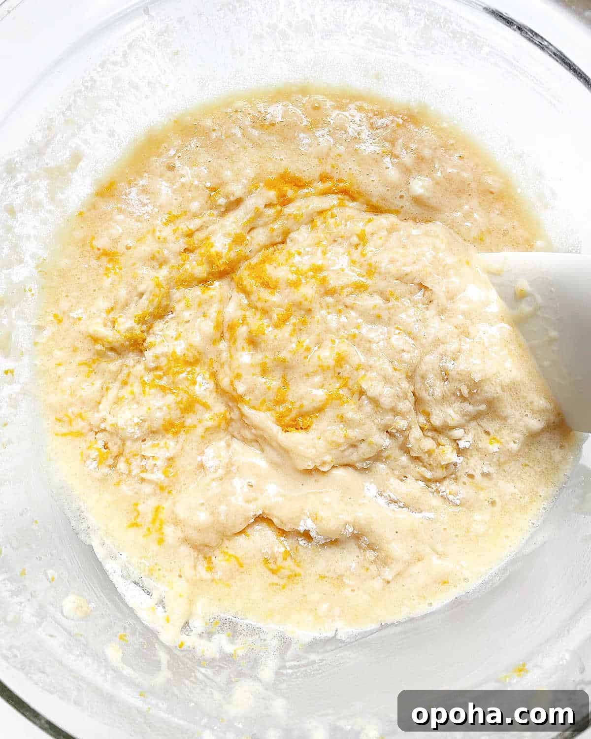 Quick Raspberry Muffins Recipe — Light, Tangy, Perfect for Brunch 7 Stirring lemon zest into muffin batter with spatula in a glass bowl.