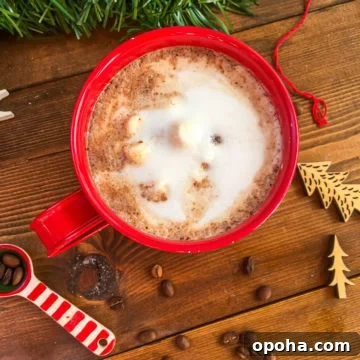 Homemade Mocha Coffee Bombs: Decadent Hot Chocolate Surprise 10 A red mug of hot chocolate topped with steamed milk on a wooden background surrounded by spilled coffee beans.