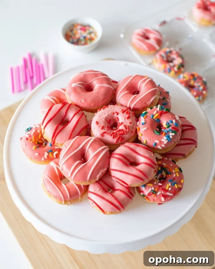 Donut Cake Tower Ideas: Show-Stopping Dessert Centerpieces 7 A platter of pink donuts decorated with white and red icing drizzles.
