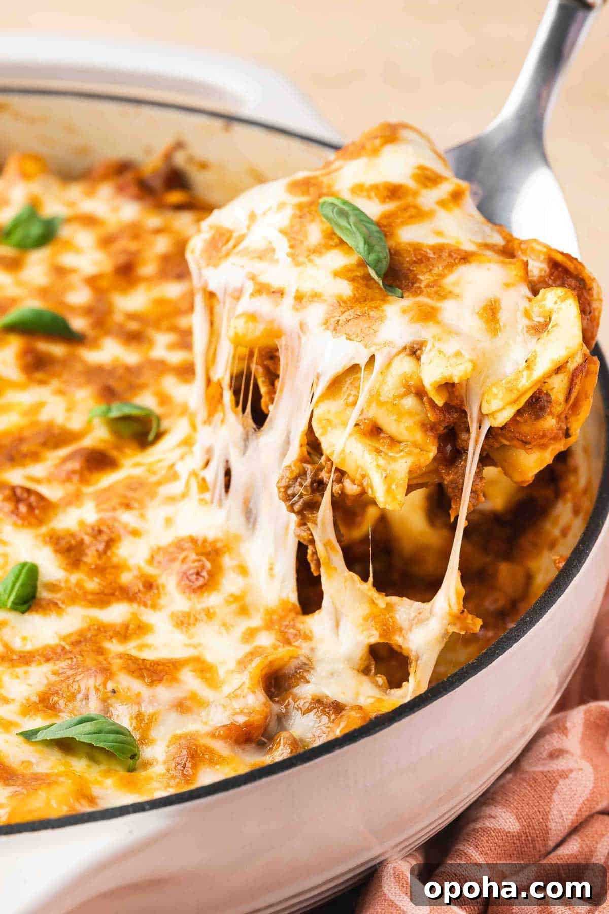 Tortellini Lasagna Bake: Cheesy Italian Pasta Casserole Recipe 8 A serving spoon scooping up tortellini lasagna from a pot, showing a cheese pull.