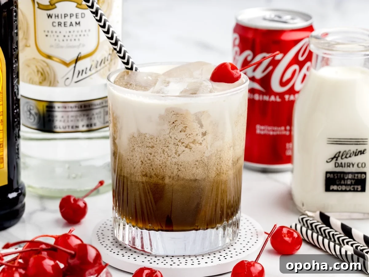 A glass of Paralyzer Drink with cream, cola, and a cherry on top sits on a coaster. Surrounding it are bottles of whipped cream vodka, cola, milk, and maraschino cherries. A striped straw is in the glass.
