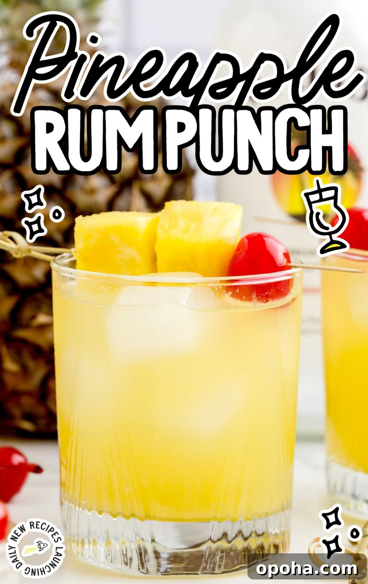 close up shot of a glass of Pineapple Rum Punch garnished with pineapples and a cherry