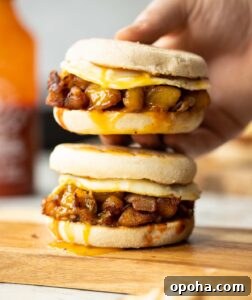 hand holding potato sandwich above another one on chopping board with yolk dripping out