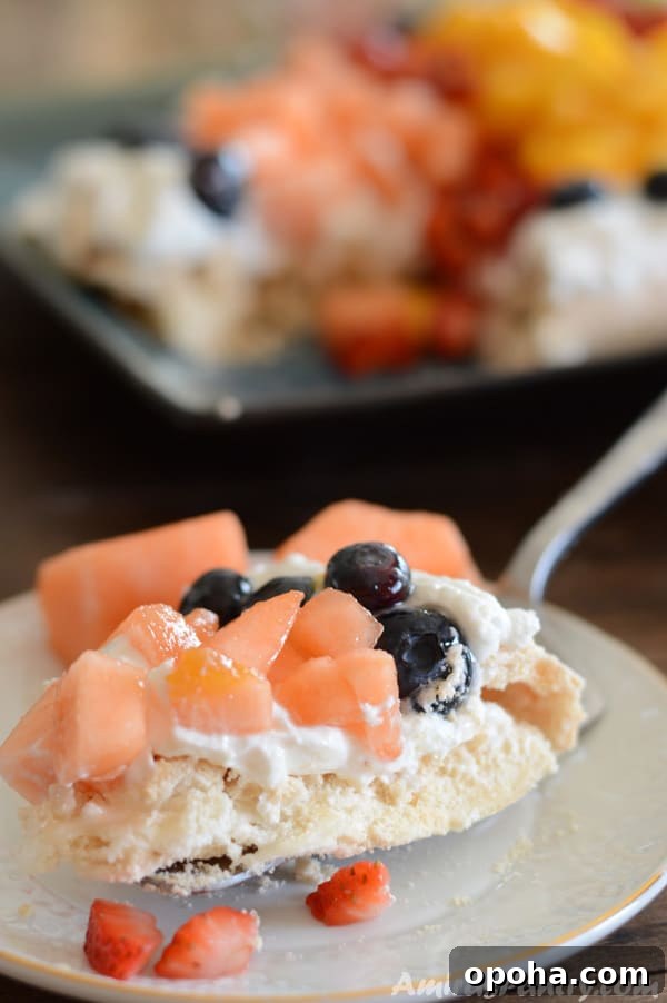Easter Pavlova Recipe with Fresh Fruit Topping 4 A close up of a piece of cake on a plate, with Pavlova and fruits