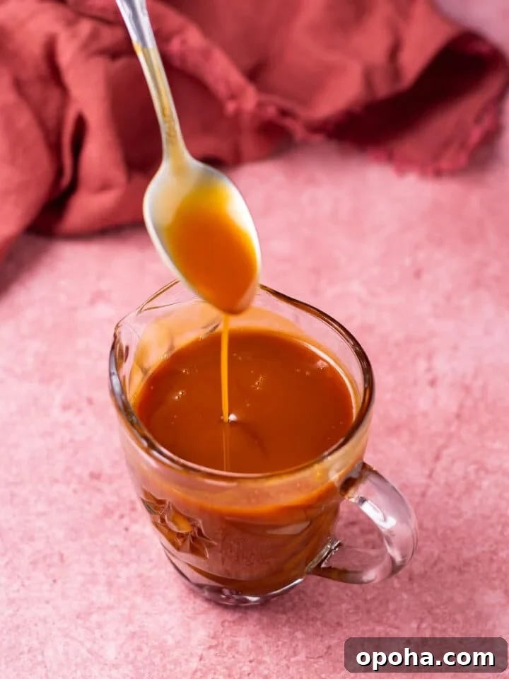Spoon drizzling salted caramel into a small pitcher of caramel syrup