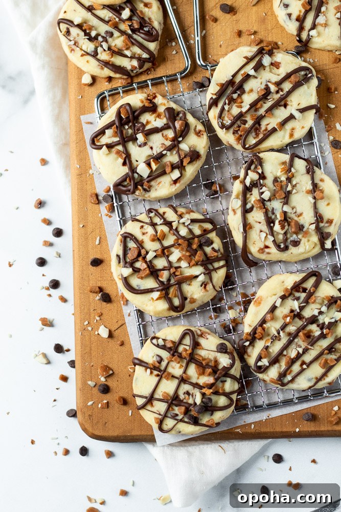 A batch of shortbread cookies topped with drizzled chocolate, almonds and toffee. 