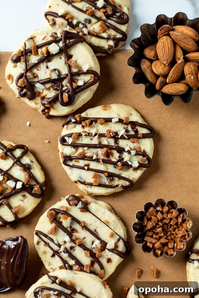 Some slice and bake cookies next to dishes of almonds and toffee bits. 
