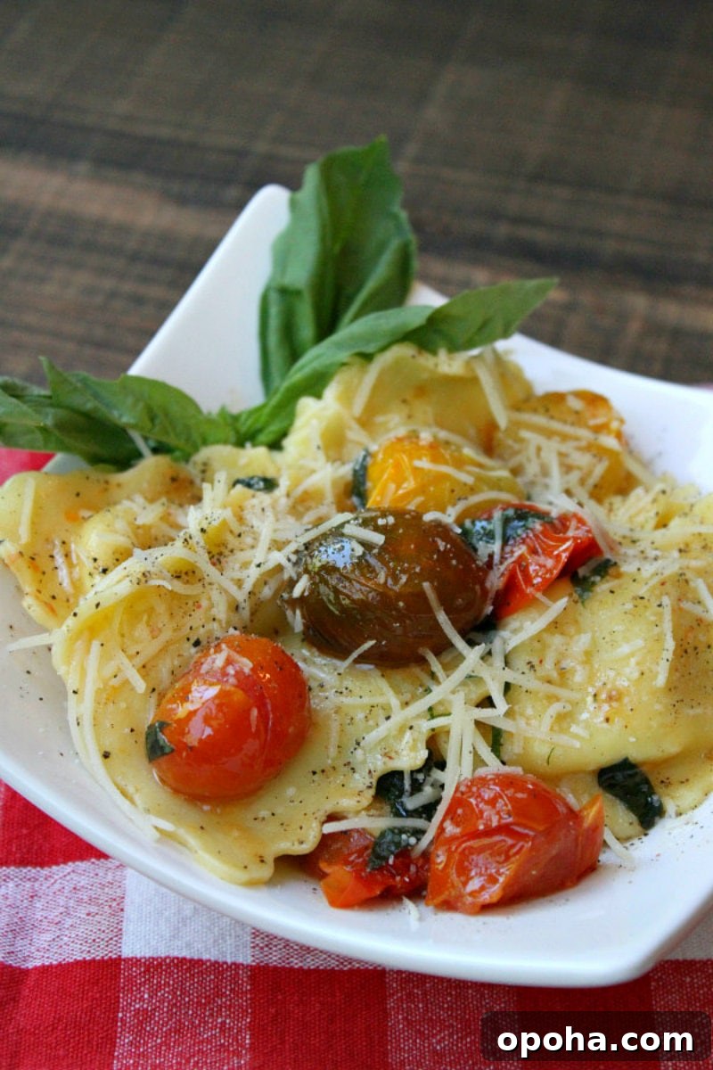 brown butter ravioli with tomatoes on a white plate set on a red/white checked napkin
