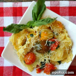 overhead shot of brown butter ravioli with tomatoes on a white plate set on a red/white checked napkin