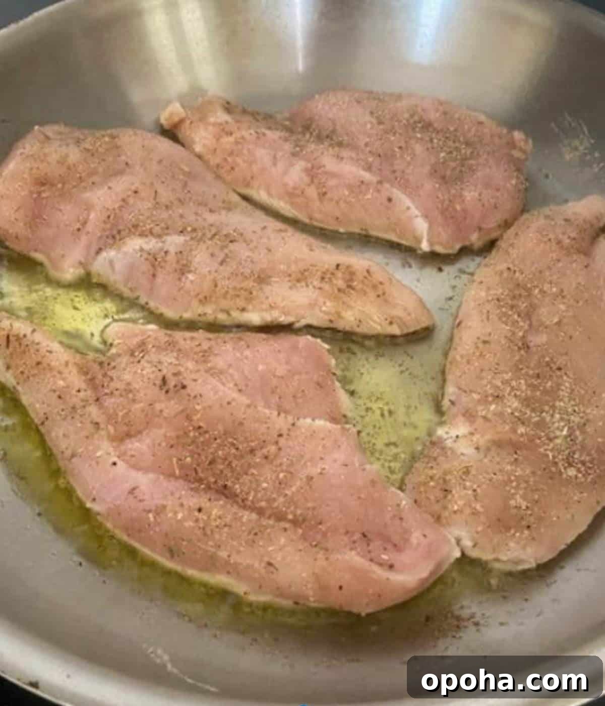 Perfectly Sautéed Chicken Breasts with Garlic and Herbs 6 Chicken breast cooking in oil in pan.