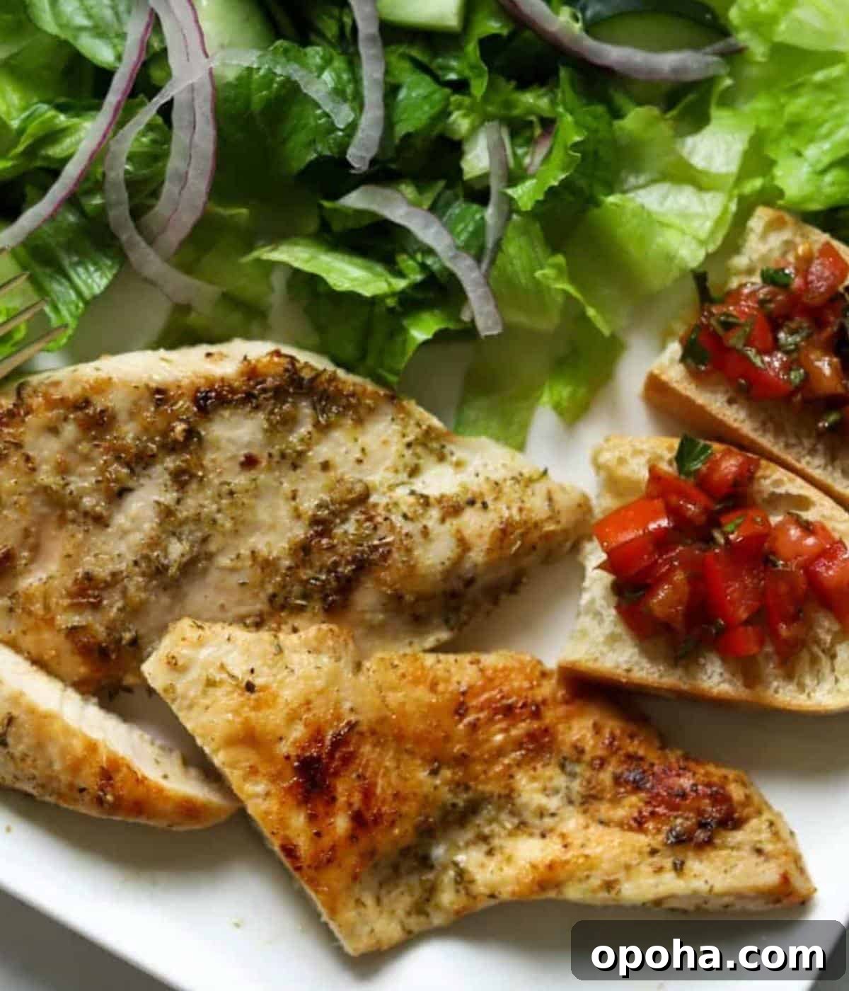 Perfectly Sautéed Chicken Breasts with Garlic and Herbs 8 Sauteed chicken breast on plate with salad on side and bread with bruschetta.