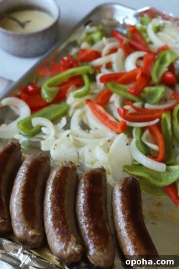 Fully cooked sausages and peppers and onions on pan.