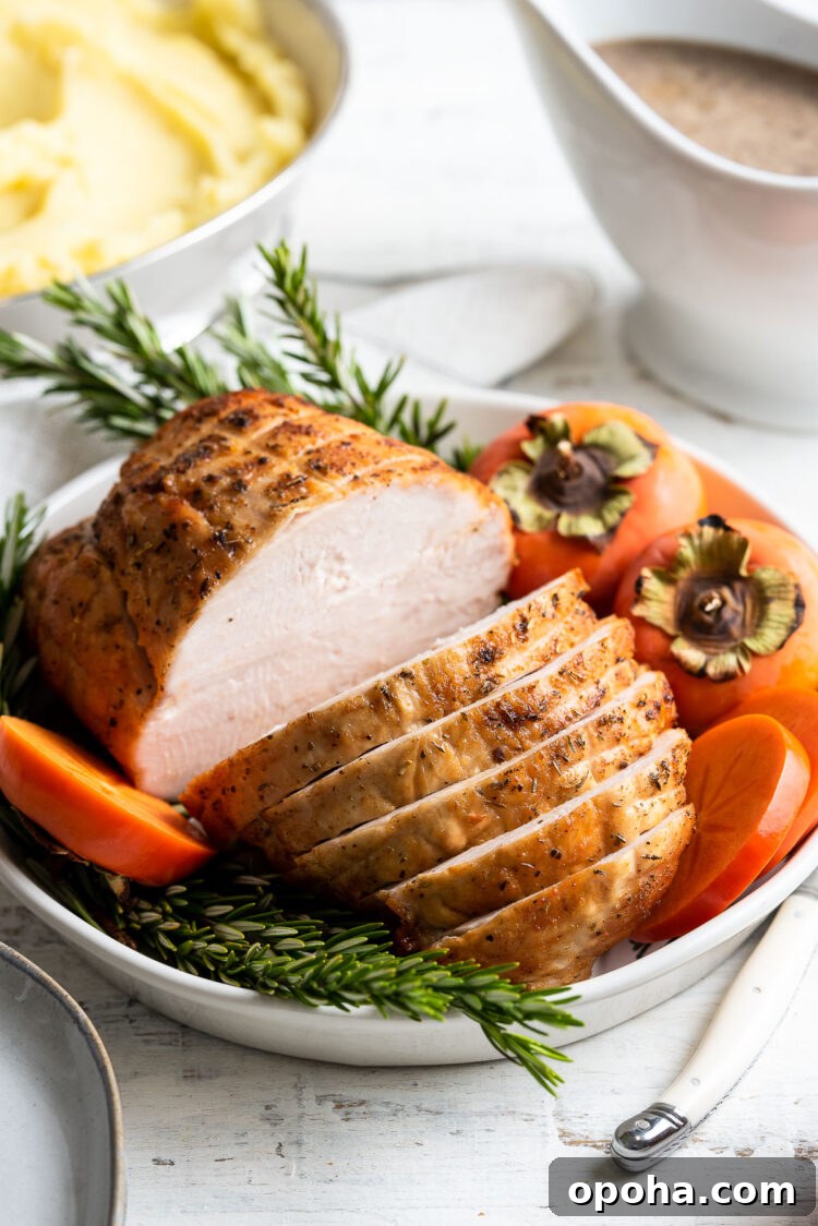 Perfectly Roasted Boneless Turkey Breast Recipe for Juicy Slices 8 Roasted Boneless Turkey Breast sliced on a platter garnished with rosemary and persimmons.