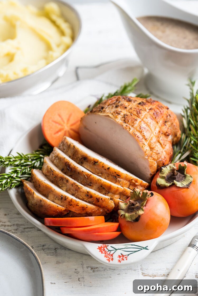 Perfectly Roasted Boneless Turkey Breast Recipe for Juicy Slices 9 Roasted Boneless Turkey Breast sliced on a platter garnished with rosemary and persimmons.