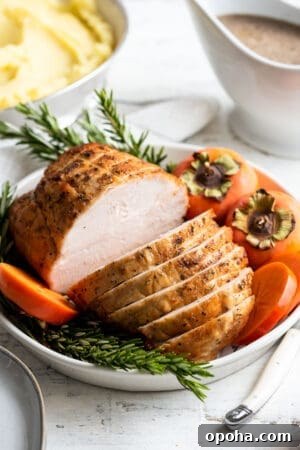 Perfectly Roasted Boneless Turkey Breast Recipe for Juicy Slices 10 Roasted Boneless Turkey Breast sliced on a platter garnished with rosemary and persimmons.