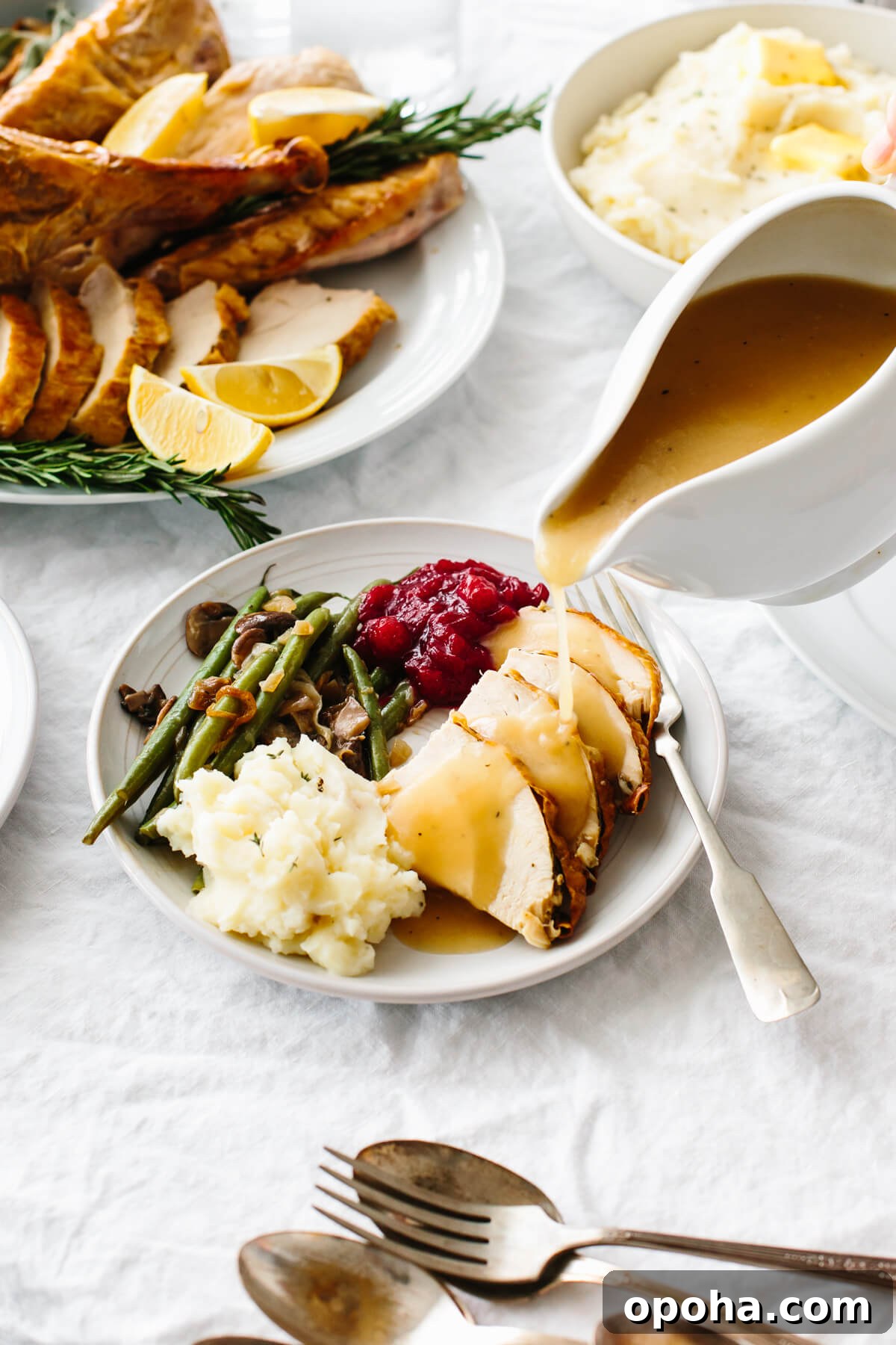 Turkey gravy pouring over a plate of Thanksgiving food.
