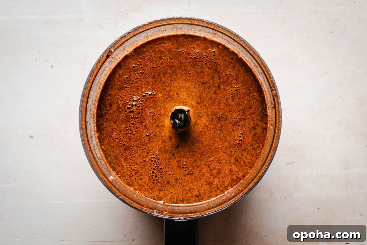 Authentic New Mexican Carne Adovada Recipe 10 Top view of a food processor filled with a thick, orange-brown sauce.