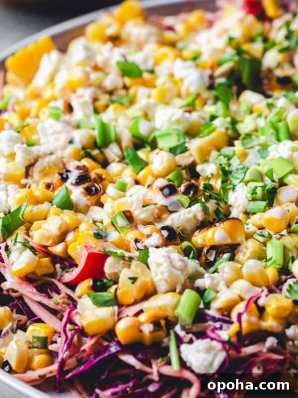 A colorful Mexican Street Corn Salad on a plate, featuring charred corn, crumbled cheese, and chopped green onions.