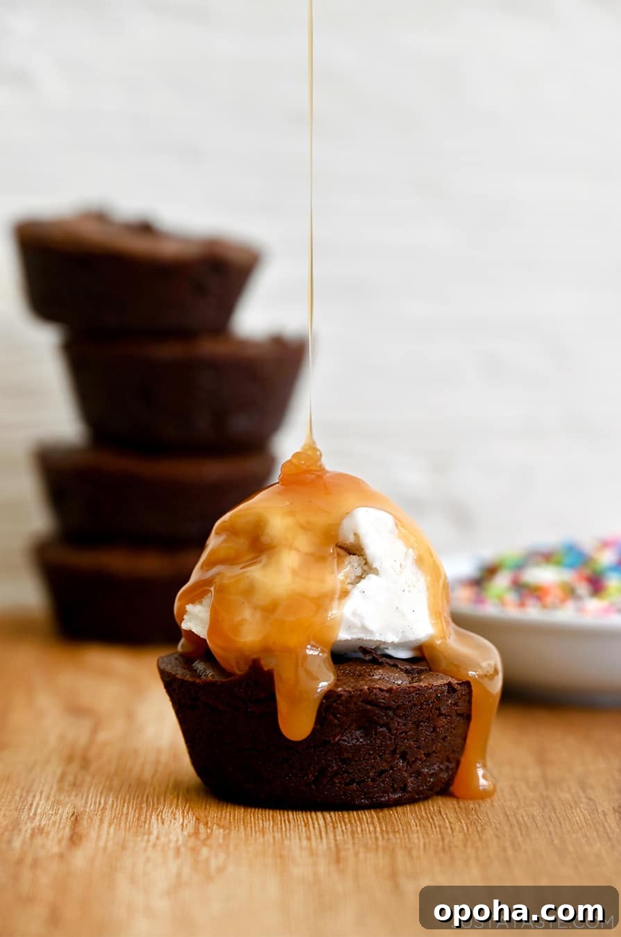 Fudgy From-Scratch Brownie Cupcakes Recipe 8 A fudgy brownie cupcake topped with a scoop of vanilla ice cream being drizzled with caramel sauce