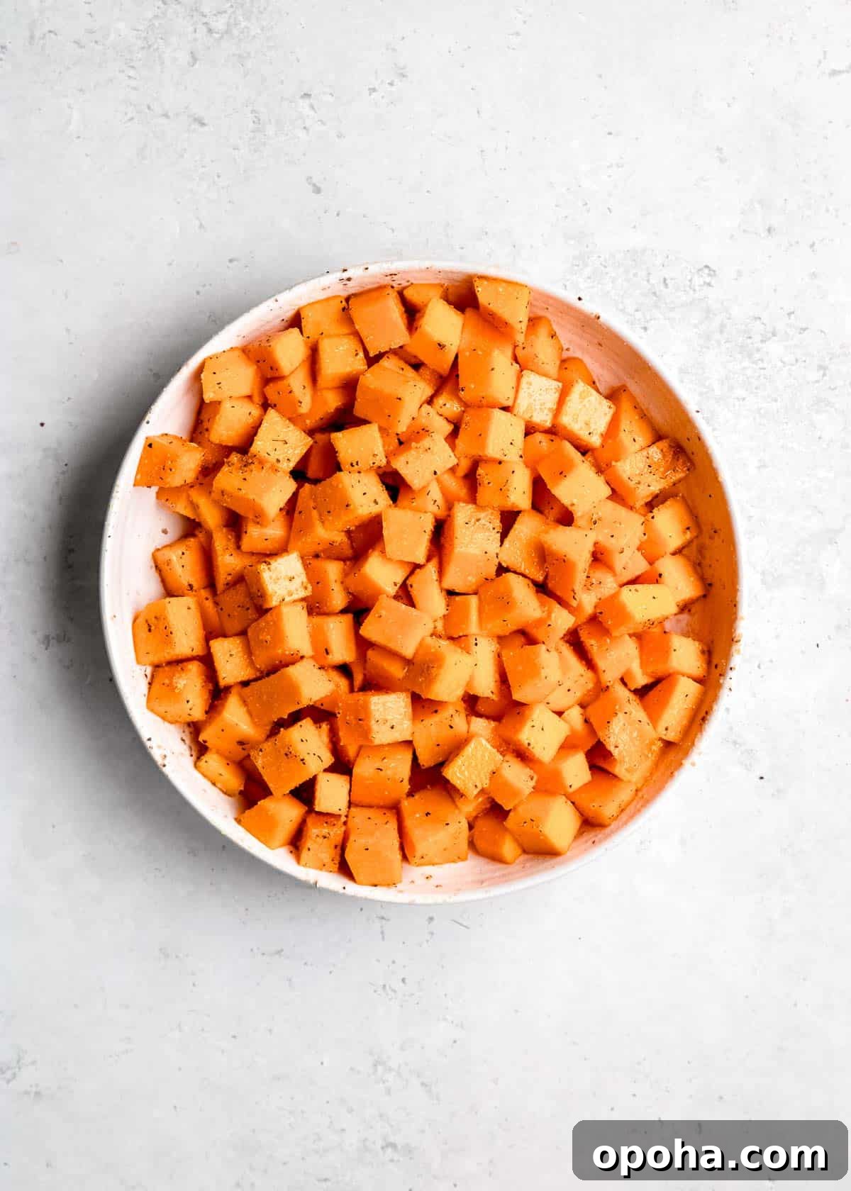 seasoned cubed butternut squash in white bowl