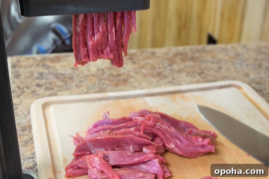 Sesame-Glazed Venison Jerky Recipe: Savory Sweet Game Meat Snack 4 erky slicer slicing venison for jerky onto a cutting board with knife