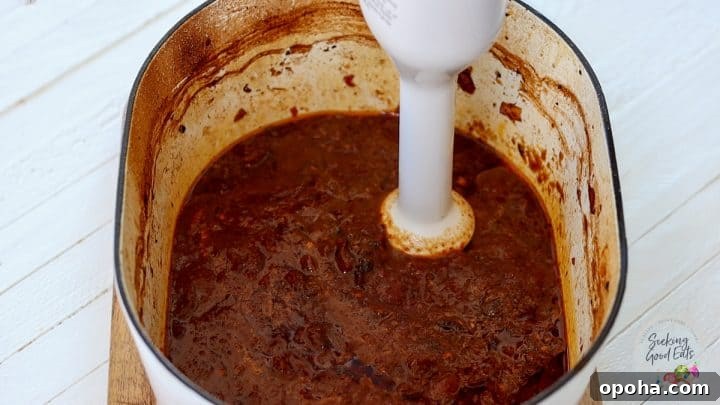 Using a handheld blender to smooth the consomme dipping sauce for the birria tacos.