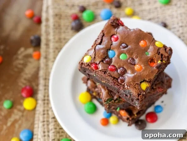 M&M brownies stacked on each other on white plate.