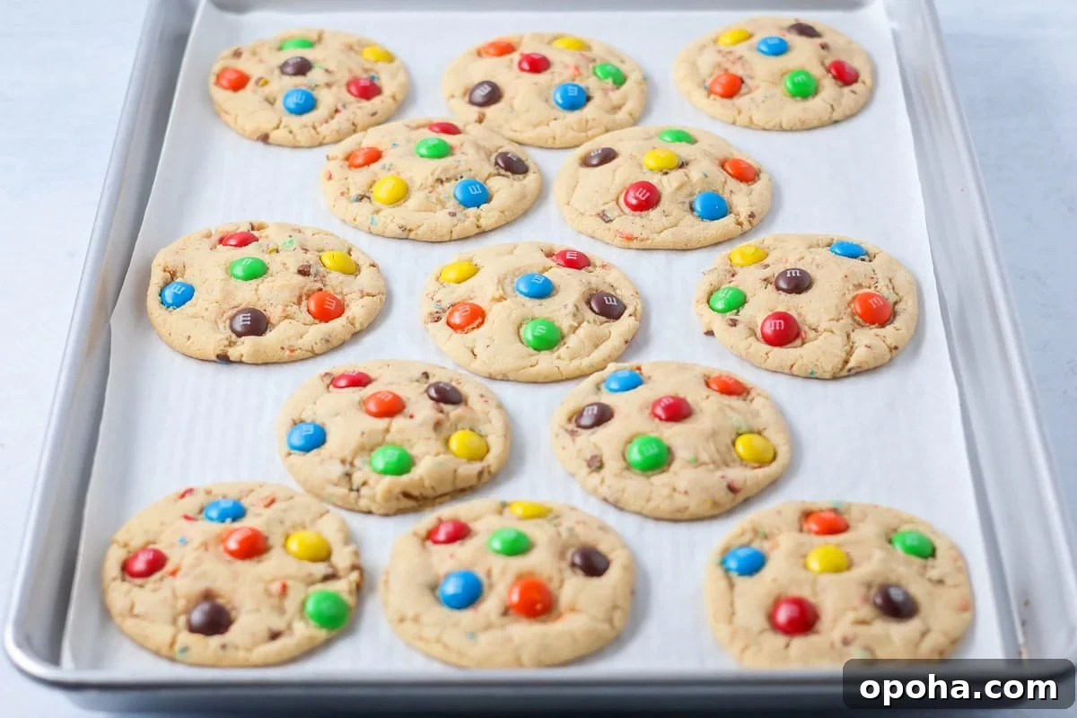 M&M cookies baked on baking sheet.