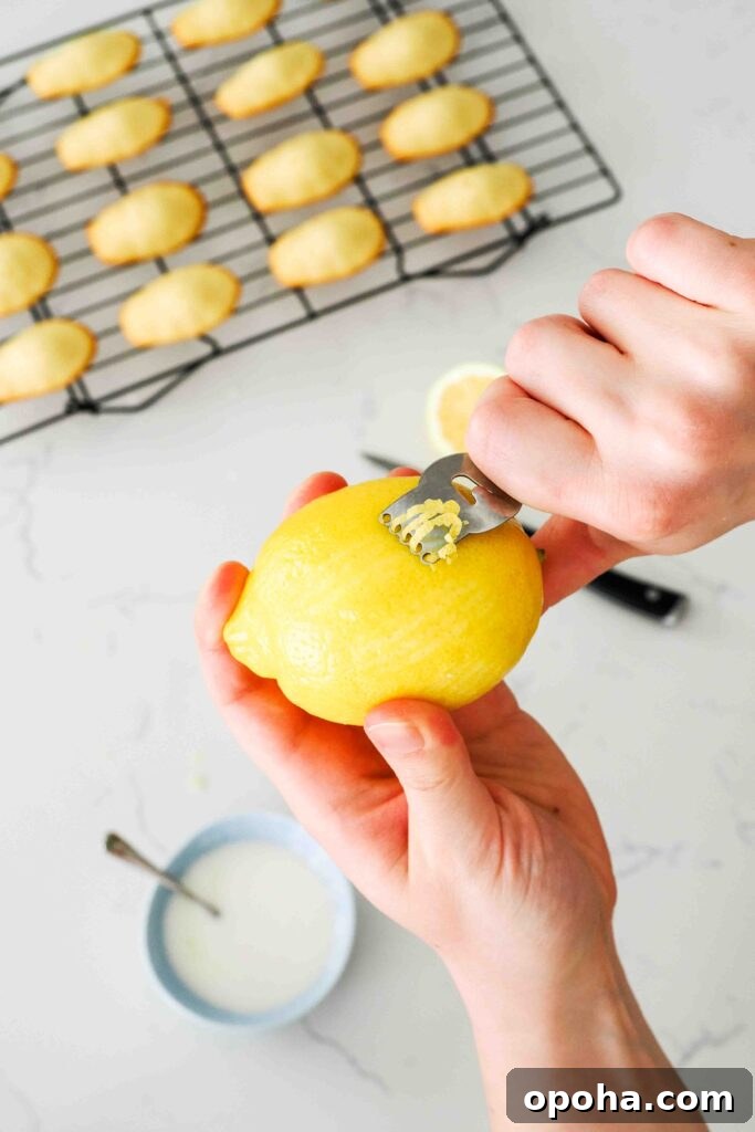 Zesty Lemon Madeleines: Classic French Tea Cakes Recipe 15 A lemon is peeled with a citrus zester for long strips of zest.