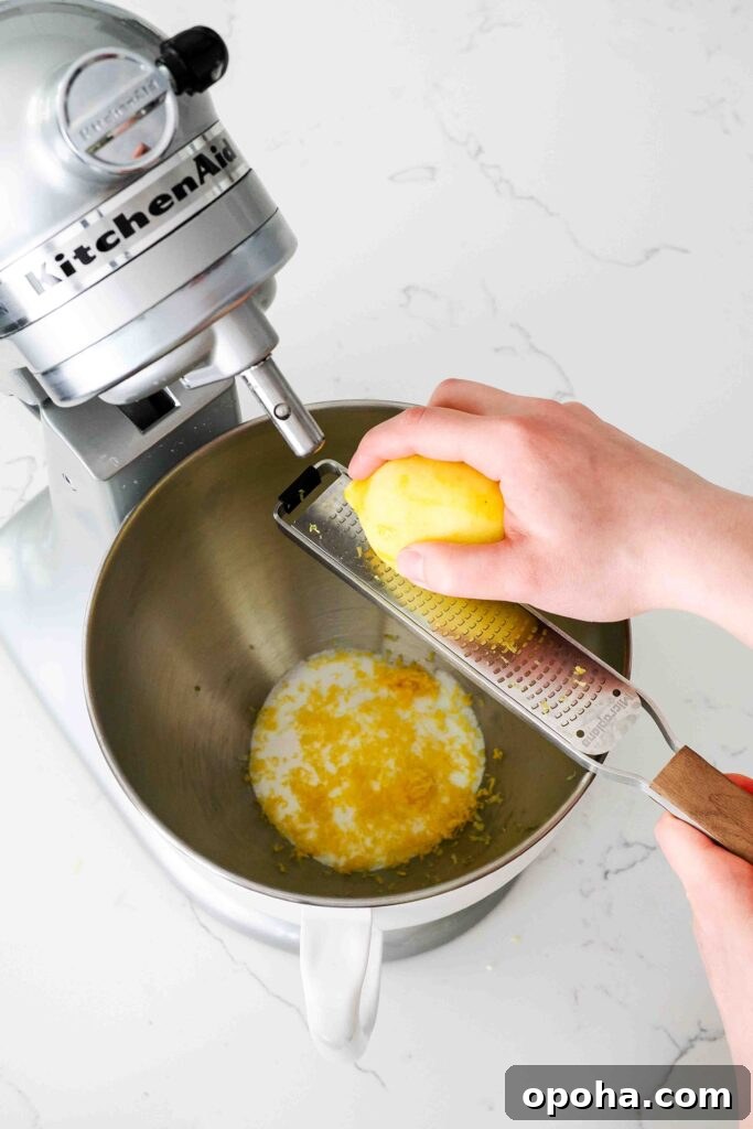 Zesty Lemon Madeleines: Classic French Tea Cakes Recipe 4 A lemon is zested into a stand mixer bowl with sugar.