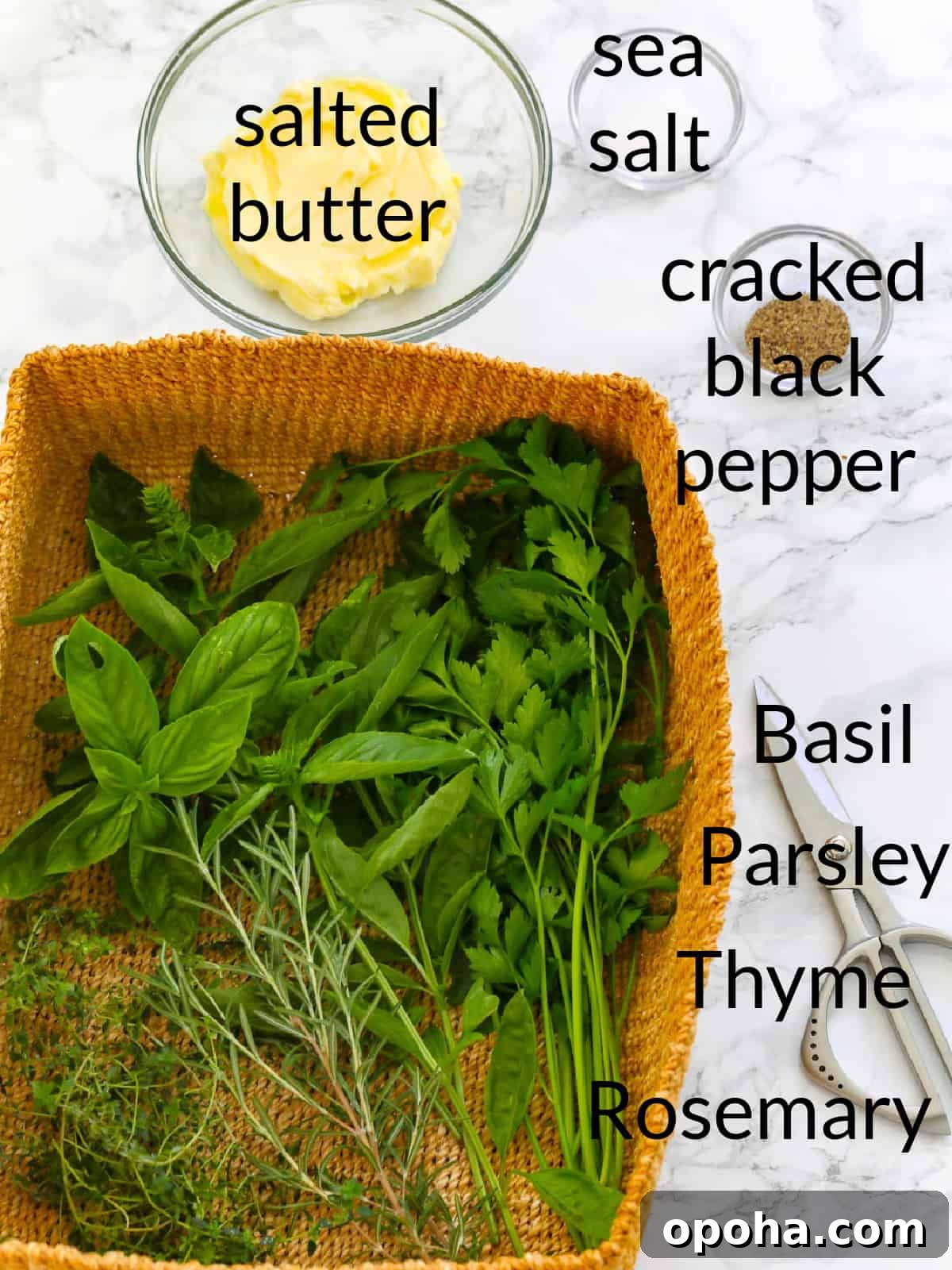 All the ingredients labeled to make herb butter including fresh herbs, butter, salt and pepper.