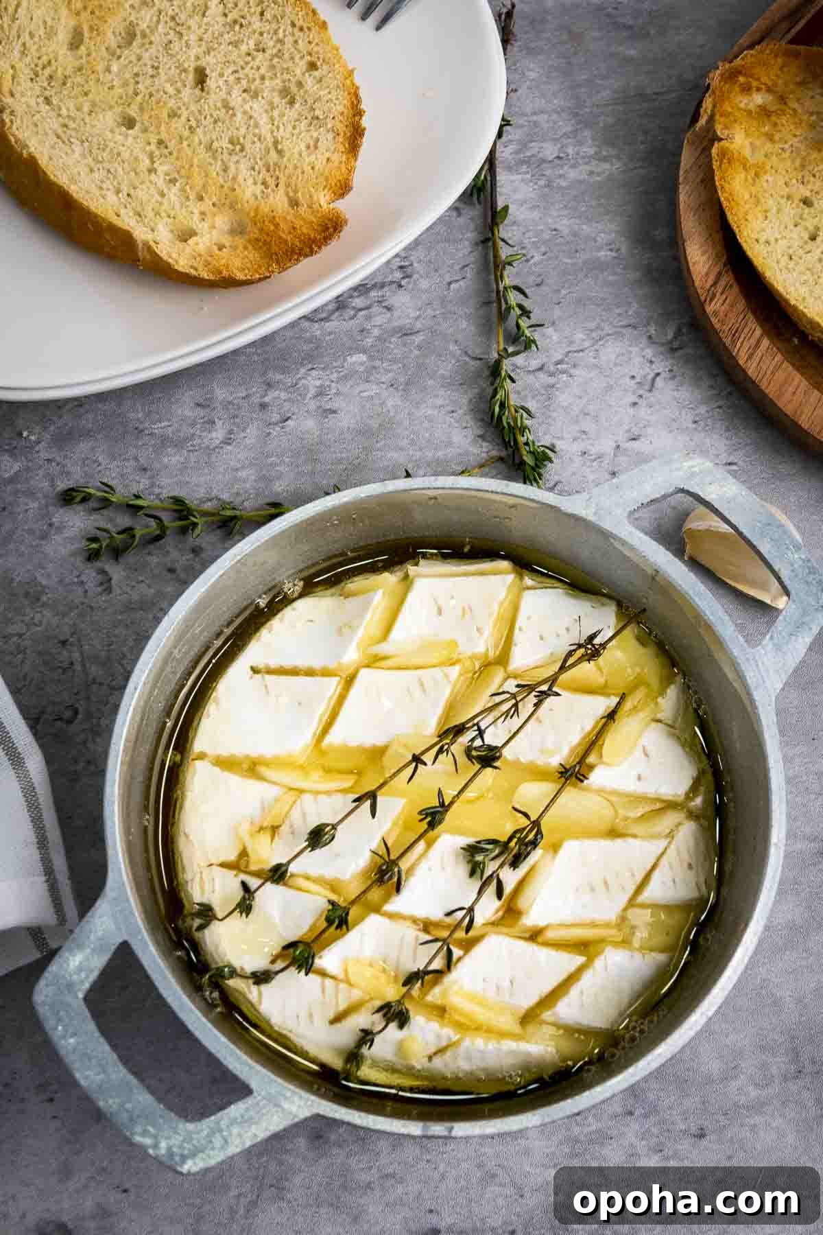 Overhead shot of baked brie garnished with fresh thyme in a small baking dish with more thyme sprigs on the side.