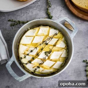 Overhead shot of baked brie garnished with fresh thyme in a small baking dish with more thyme sprigs on the side.