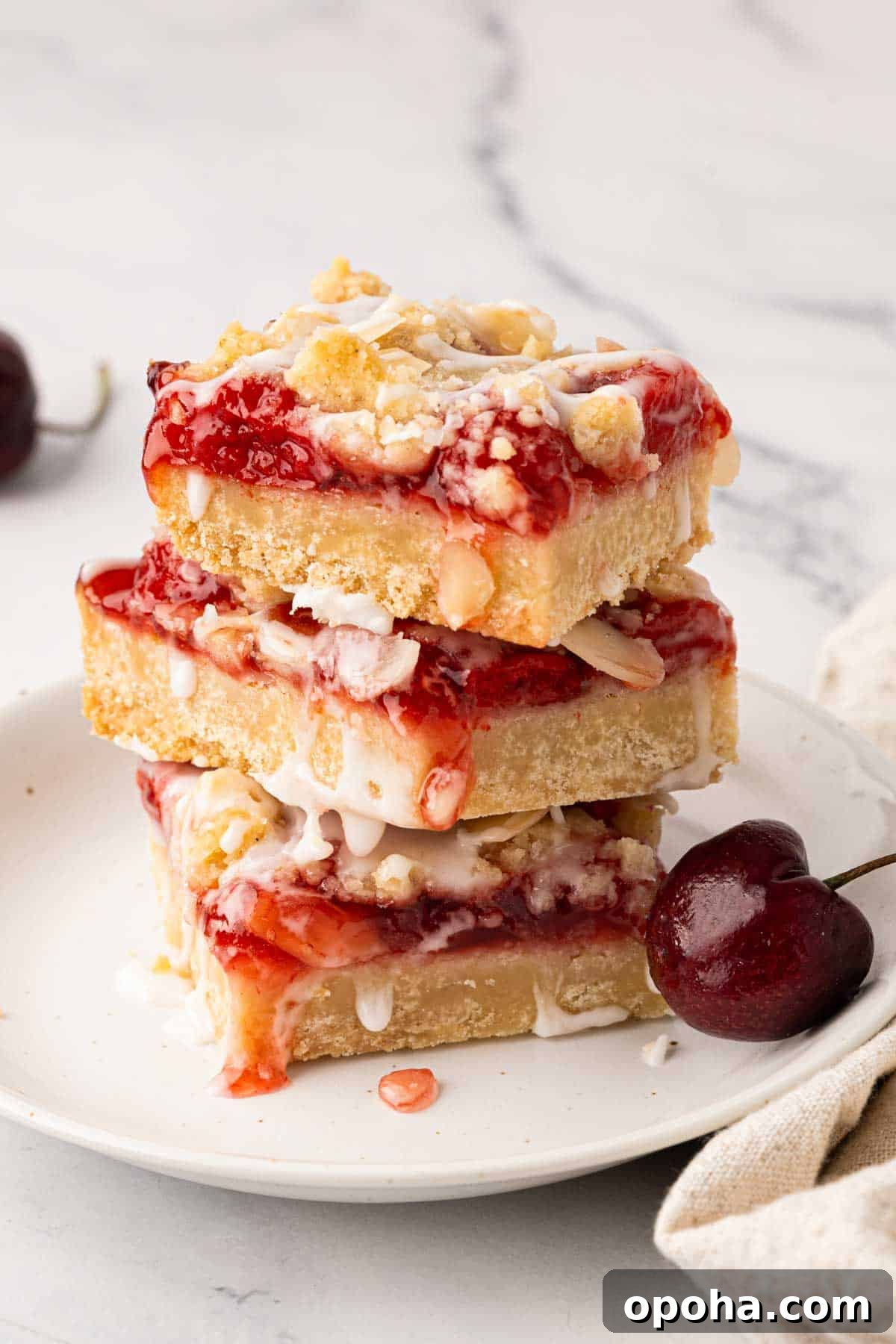 Cherry Pie Bars Recipe: Easy Homemade Cherry Dessert Bars 20 A stack of three cherry pie bars on a white plate.