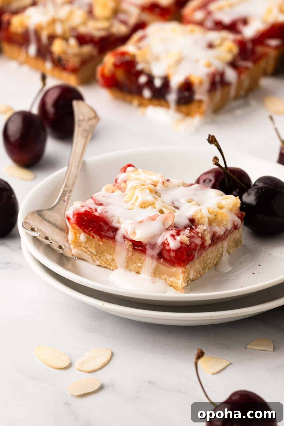 Cherry Pie Bars Recipe: Easy Homemade Cherry Dessert Bars 3 A cherry pie bar on a white plate with a fork.