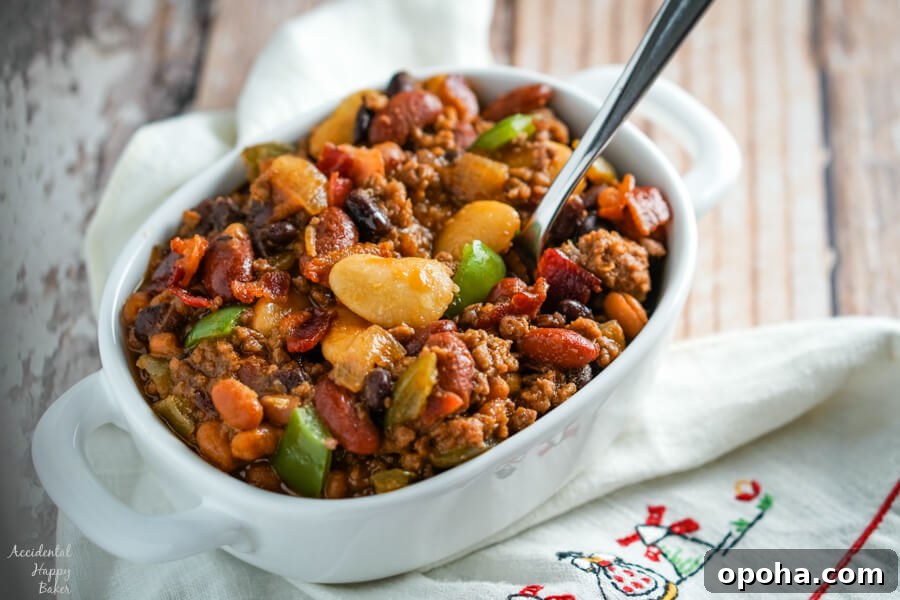 A bowl of Slow Cooker Calico Beans sitting on a napkin with a spoon.