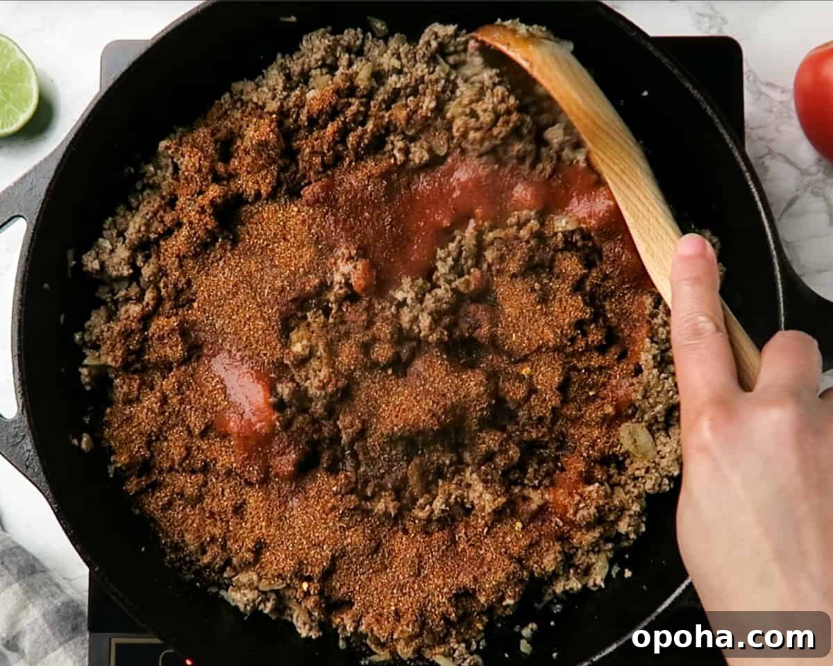 Taco Meat Recipe: Skillet, Instant Pot, or Crock Pot Options 5 seasonings and tomato sauce being added to the ground beef in the skillet