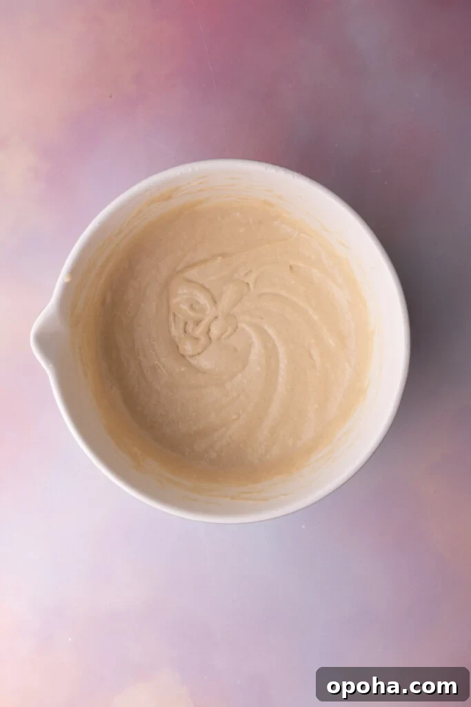 Homemade waffle batter in a mixing bowl on a colorful background.