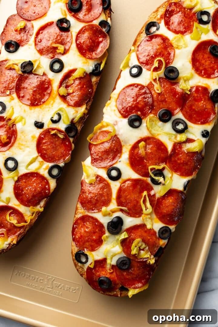 two halves of a loaf of french bread pizza on a baking tray
