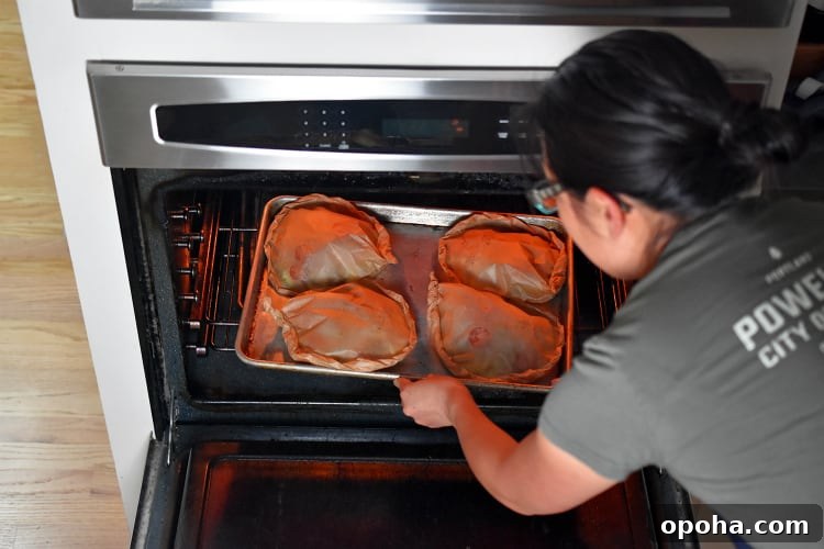 Placing a tray of Lemon Garlic Chicken Parchment Packets into the oven.