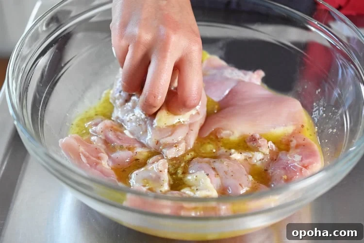 Adding boneless, skinless chicken thighs to a bowl of lemon garlic marinade.