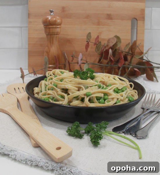 A plate of fettuccine with peas, covered in a peppery cheese sauce.