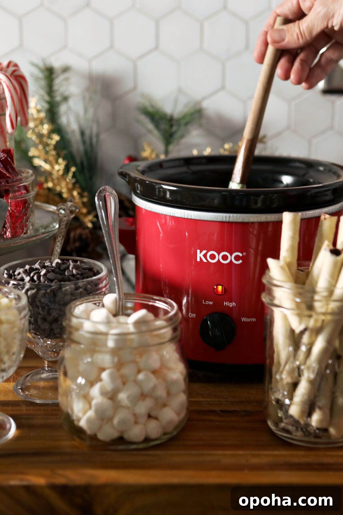 Create a DIY Hot Chocolate Bar for Parties and Gatherings 5 A hand stirs a slow cooker of hot chocolate on a hot chocolate board