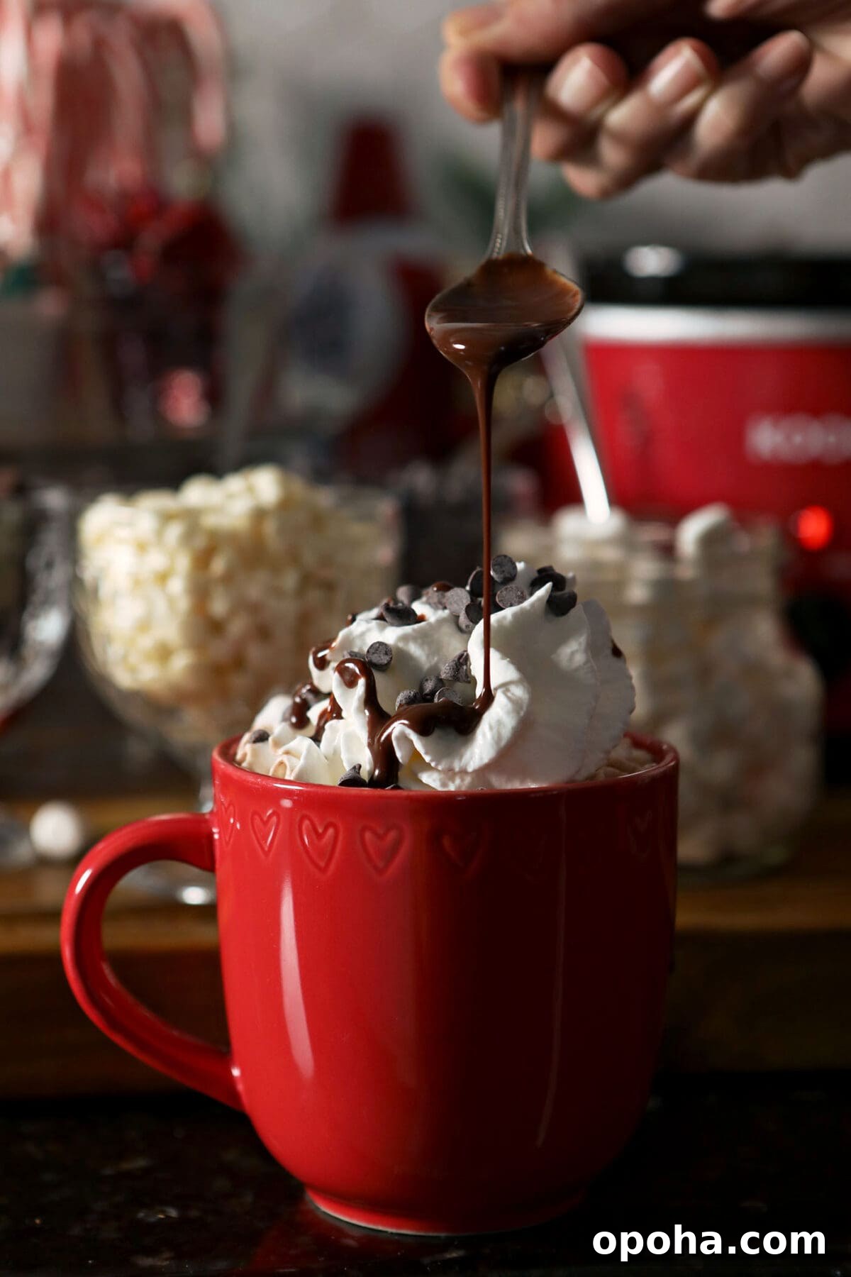 Create a DIY Hot Chocolate Bar for Parties and Gatherings 6 Chocolate syrup pours on top of a red mug of cocoa topped with whipped cream
