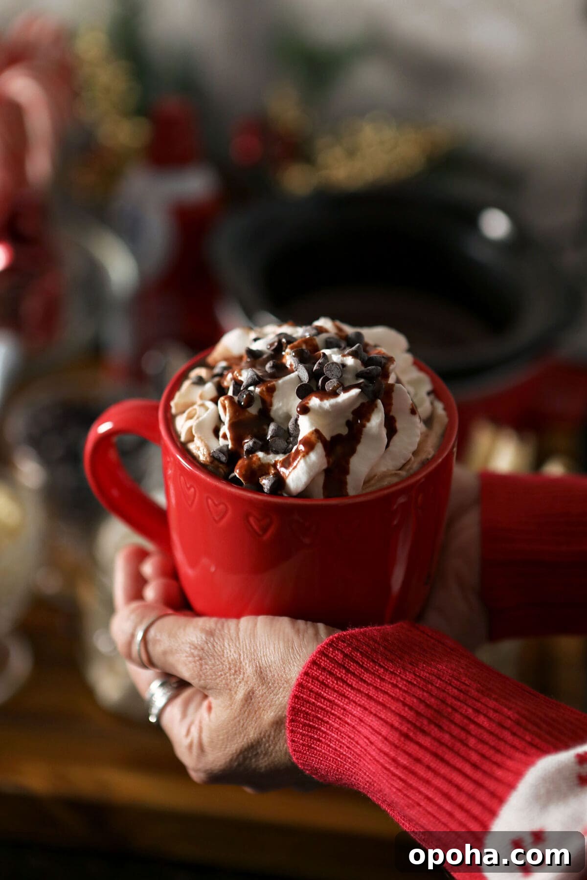 Create a DIY Hot Chocolate Bar for Parties and Gatherings 7 A woman holds a red mug of cocoa topped with whipped cream and chocolate sauce