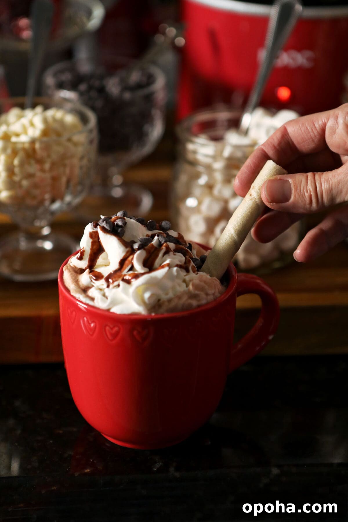 Create a DIY Hot Chocolate Bar for Parties and Gatherings 8 A hand sticks a rolled cookie into a whipped cream topped mug of cocoa