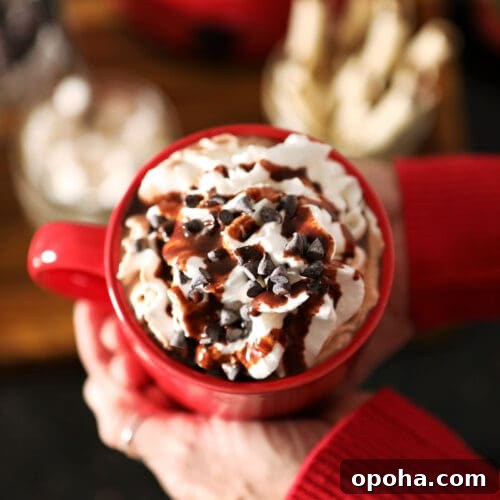 Create a DIY Hot Chocolate Bar for Parties and Gatherings 9 A woman holds a red mug of cocoa between her two hands above a hot chocolate bar