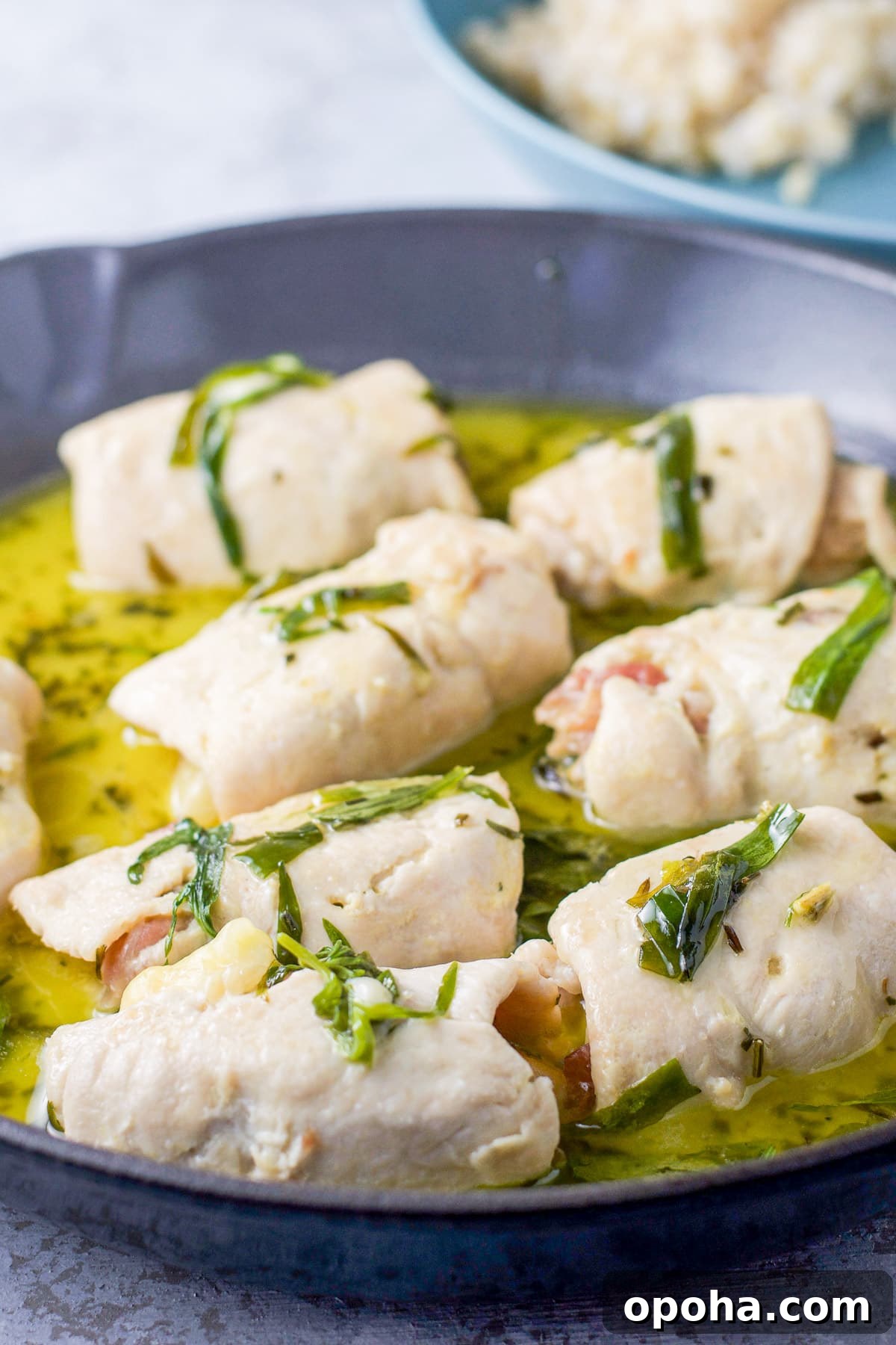 A pan with the chicken rolls in a butter sauce